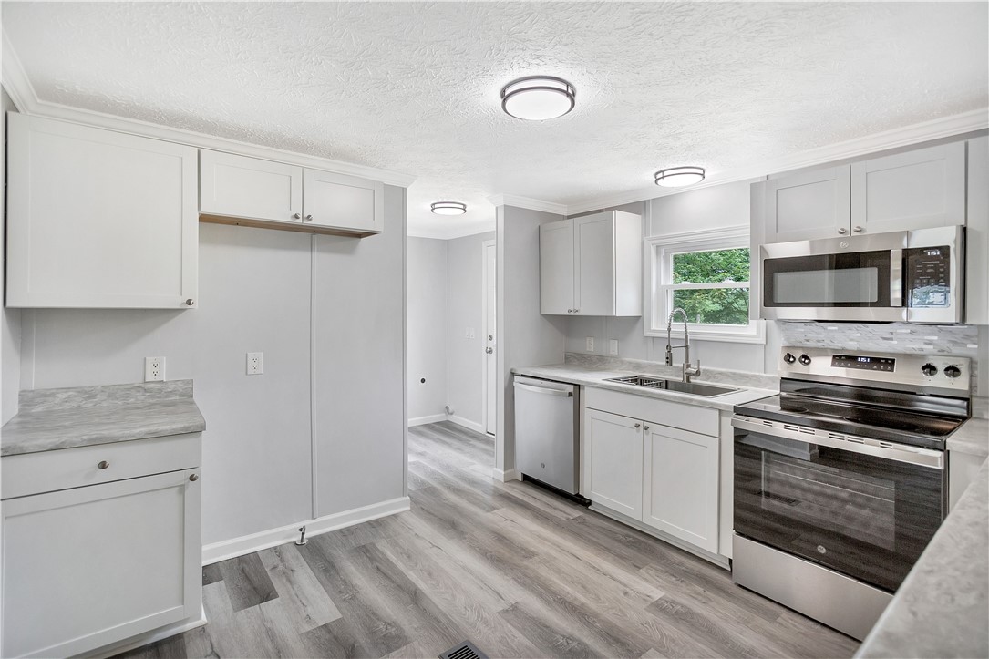 403 Hancox Place Westminster, SC 29693 - Photo 15 of 39 A contemporary kitchen features bright white cabinetry and sleek stainless steel appliances.