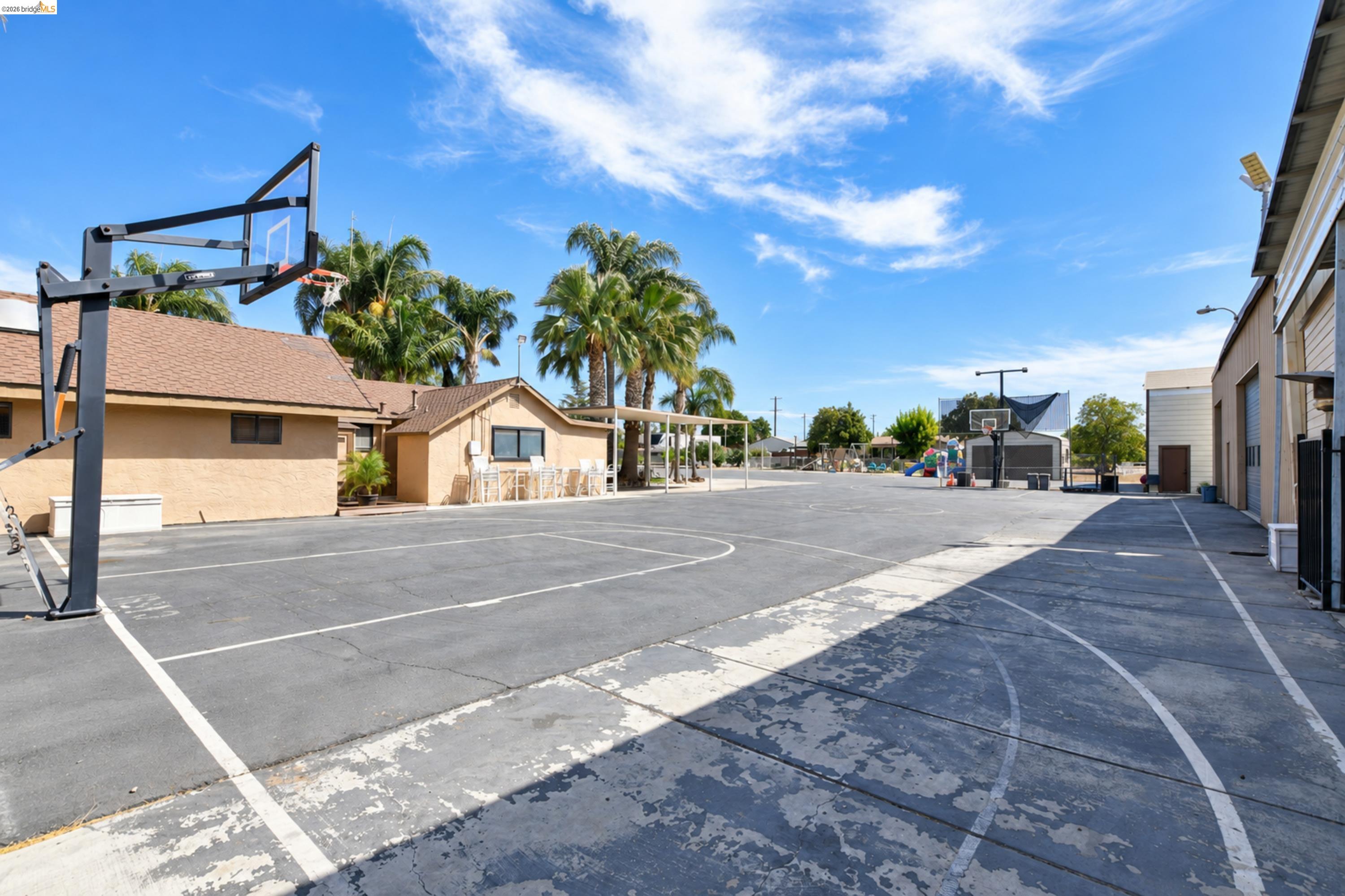 340 West Bolton Road Oakley, CA 94561 - Photo 74 of 87 Paved sports court featuring multiple basketball hoops, surrounded by low-rise buildings and mature palm trees