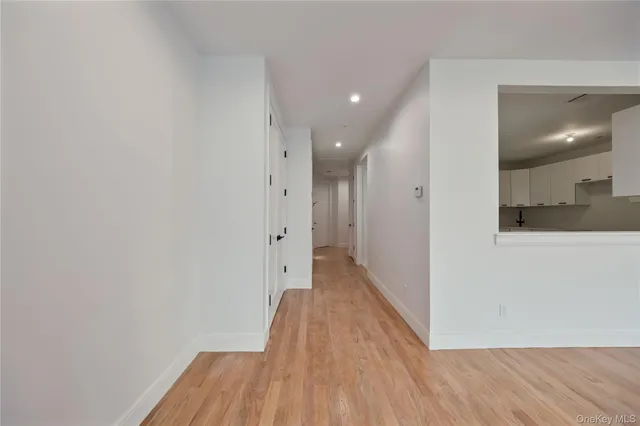 a view of an empty room with wooden floor and window