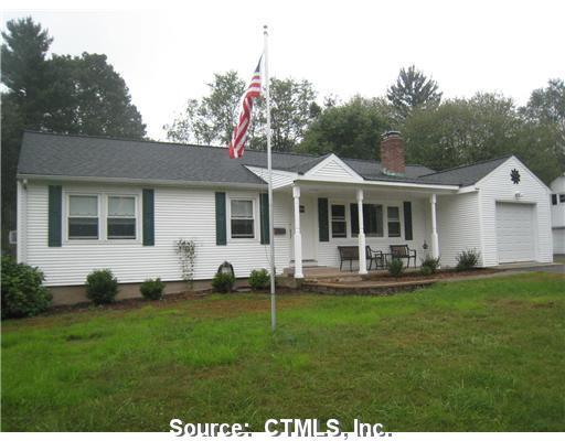a front view of a house with a garden and trees