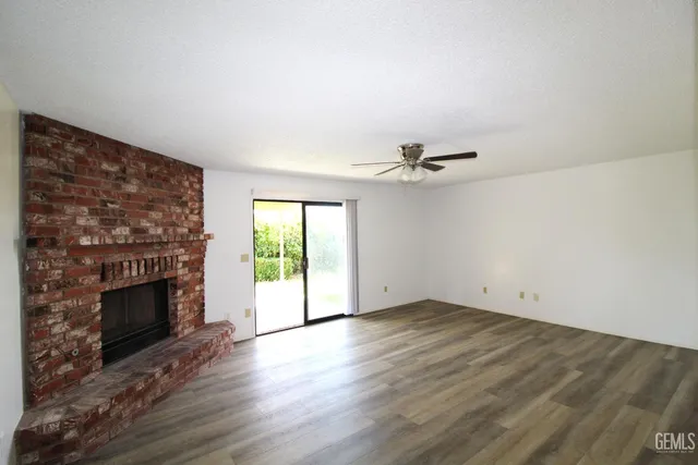 an empty room with windows fireplace and wooden floor