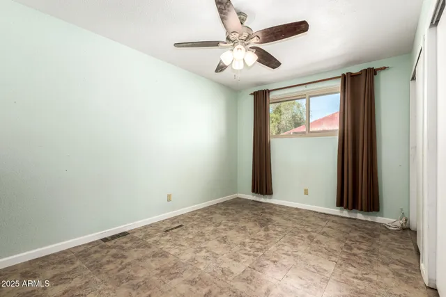 an empty room with windows and fan