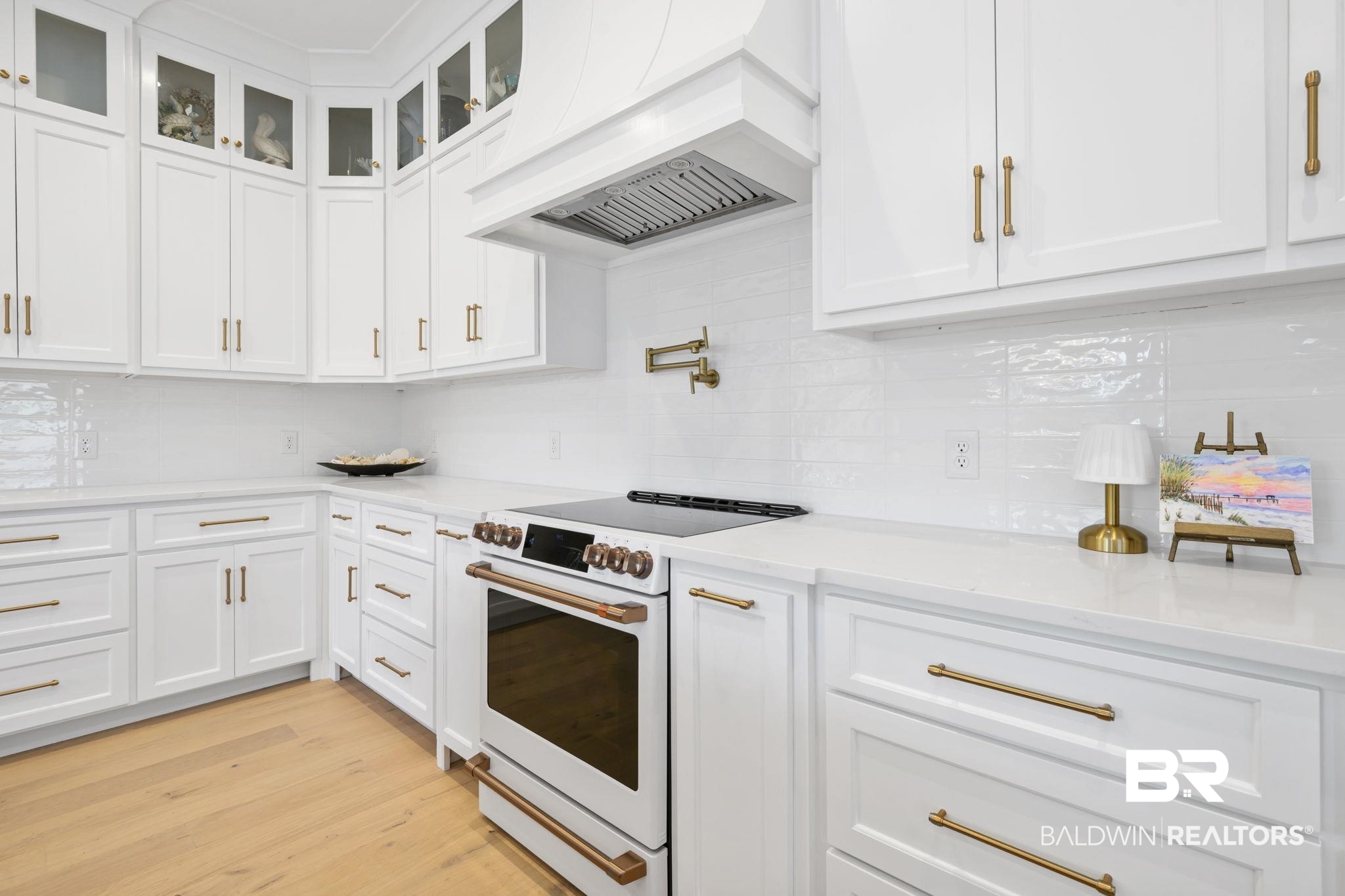 30313 River Road Orange Beach, AL 36561 - Photo 16 of 50 Kitchen with white electric stove, custom exhaust hood, white cabinets, and light stone counters