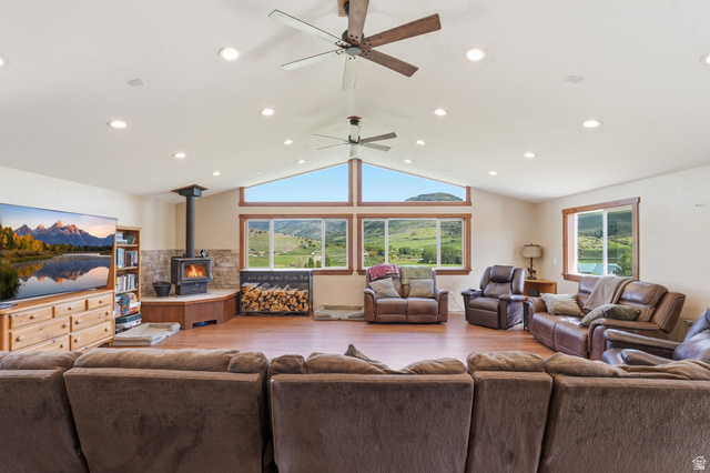 8066 North Valley View Heights Preston, ID 83263 - Photo 8 of 34 Spacious living area featuring wood-finish flooring, a wood-burning stove with stone surround, recessed lighting, and multiple ceiling fans