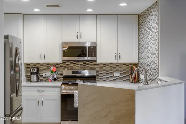 a view of kitchen with stainless steel appliances granite countertop a refrigerator and a stove top oven