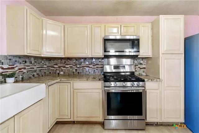 a kitchen with white cabinets and stainless steel appliances