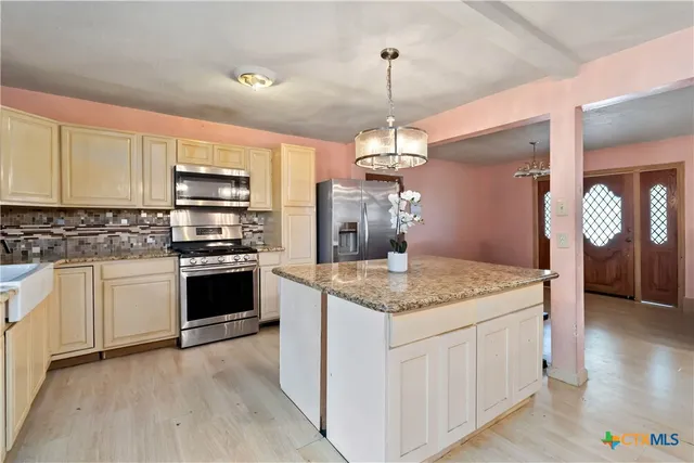 a kitchen with kitchen island granite countertop a sink a stove and refrigerator