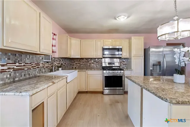 a kitchen with stainless steel appliances granite countertop a sink stove and refrigerator