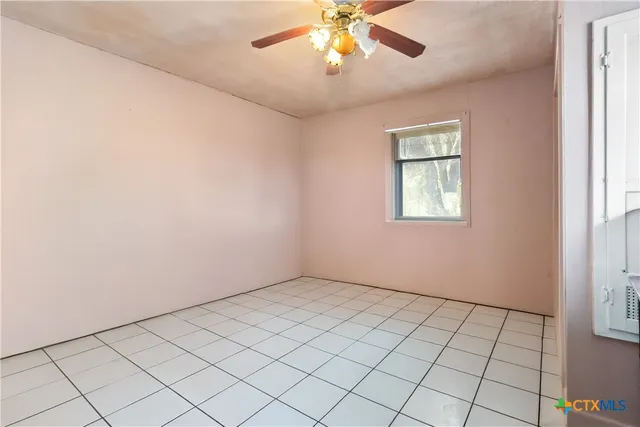 an empty room with windows and chandelier fan