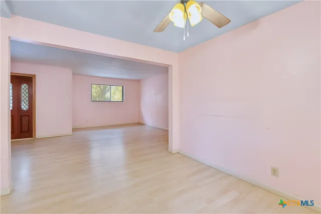 an empty room with a chandelier fan and windows