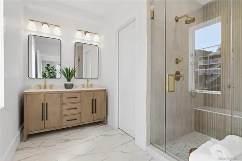 a bathroom with a double vanity sink mirror and shower