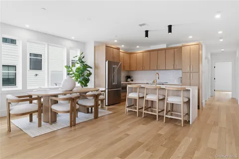 a kitchen with stainless steel appliances kitchen island granite countertop a table chairs sink and cabinets