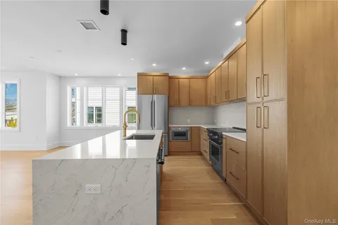 a kitchen with stainless steel appliances granite countertop a refrigerator a sink dishwasher a stove and a dining table with wooden floor