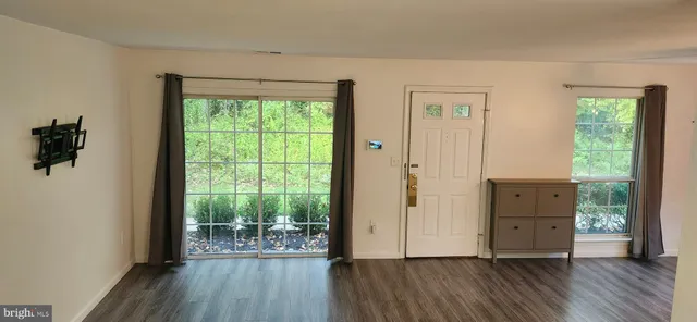 an empty room with wooden floor a ceiling fan and windows