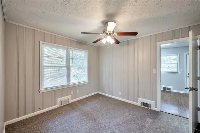 an empty room with chandelier fan and windows