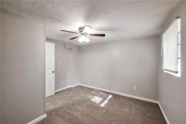 an empty room with a chandelier fan and windows