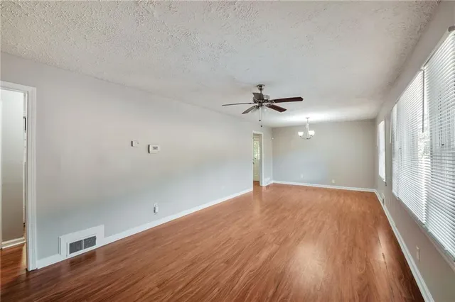an empty room with wooden floor fan and windows