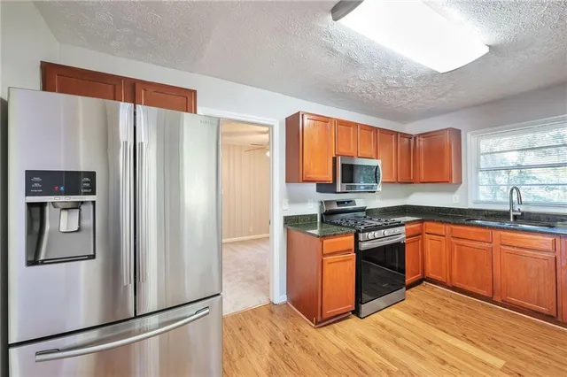 a kitchen with stainless steel appliances granite countertop a refrigerator stove top oven and sink
