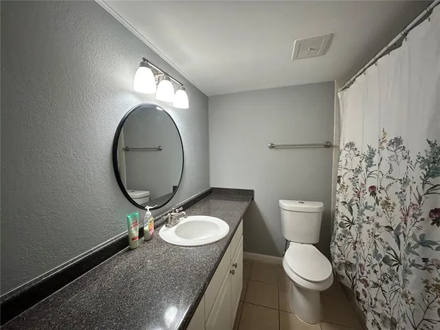 a bathroom with a granite countertop toilet sink and mirror