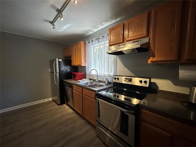 a kitchen with stainless steel appliances granite countertop a stove refrigerator and microwave