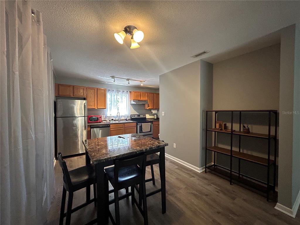 507 Northwest 39th Road, Unit 221 Gainesville, FL 32607 - Photo 19 of 19 a kitchen with a dining table chairs refrigerator and cabinets