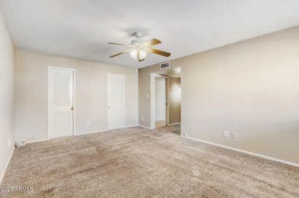 an empty room with windows and fan