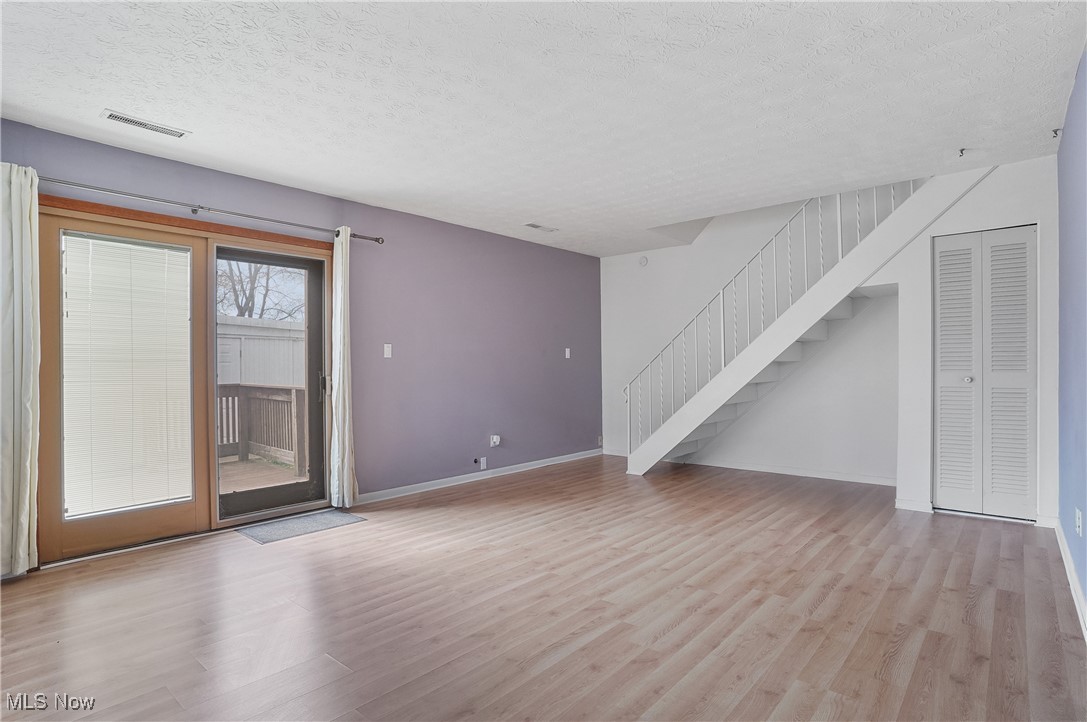 2500 Raber Road Uniontown, OH 44685 - Photo 21 of 31 Unfurnished living room with stairway, wood finished floors, baseboards, visible vents, and a textured ceiling