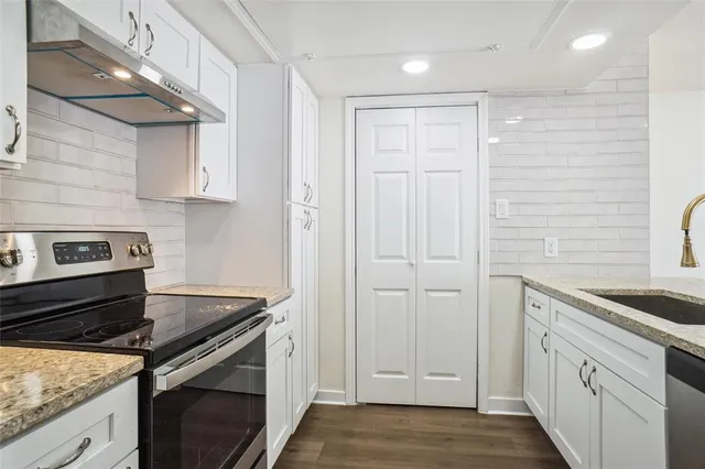 a kitchen with stainless steel appliances granite countertop white cabinets and a stove
