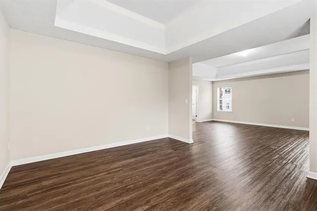 a view of an empty room with wooden floor and windows