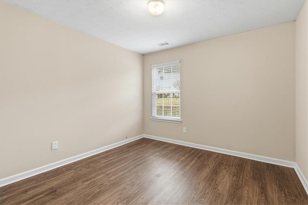 2827 Riders Court Northeast Dacula, GA 30019 - Photo 36 of 41 an empty room with wooden floor and windows