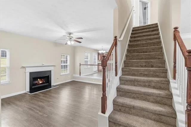 a view of an empty room with wooden floor fireplace and a window
