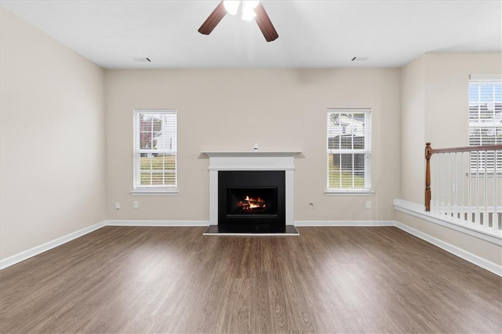 2827 Riders Court Northeast Dacula, GA 30019 - Photo 8 of 41 an empty room with wooden floor fireplace and windows