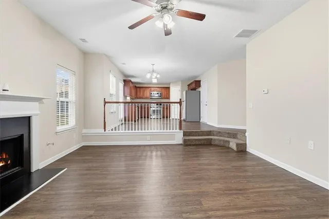 a view of an empty room with wooden floor fireplace and a window