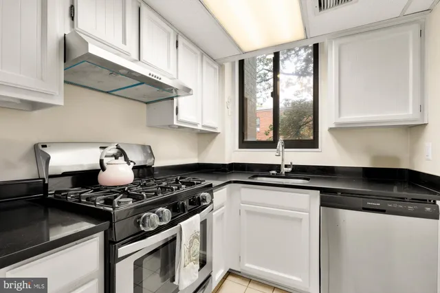 a kitchen with granite countertop a stove sink and cabinets