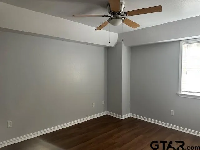 an empty room with a window and a ceiling fan