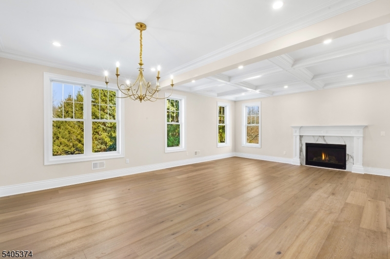 502 Tiffany Way Watchung, NJ 07069 - Photo 3 of 41 an empty room with wooden floor chandelier and fireplace