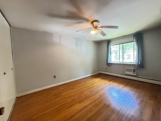 an empty room with wooden floor ceiling fan and windows