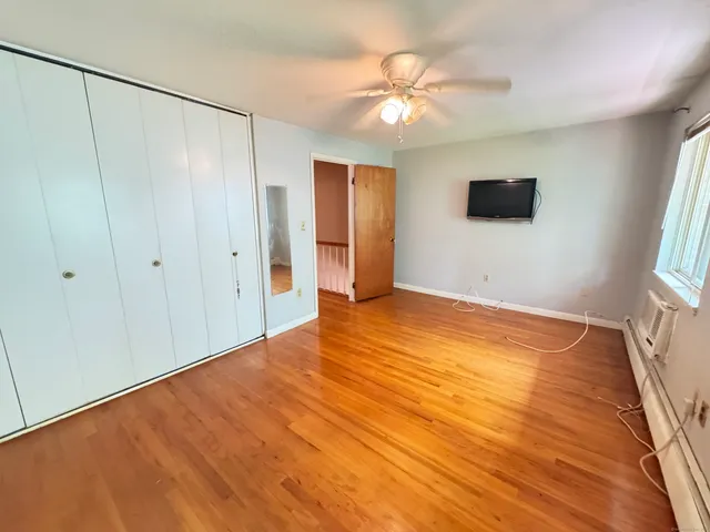 a view of an empty room with window and wooden floor