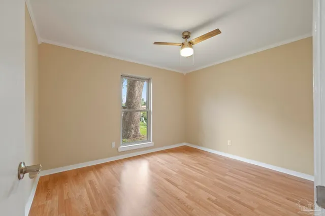 an empty room with wooden floor fan and windows