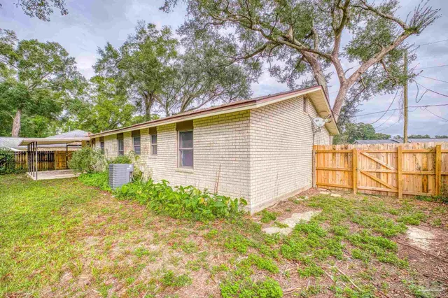 a backyard of a house with plants and large tree