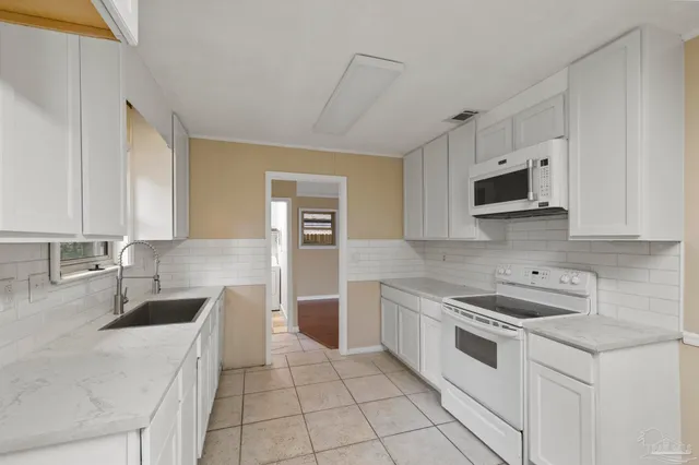 a kitchen with granite countertop a sink a stove top oven and cabinets
