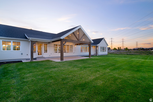 1952 South Comanche Circle Farmington, UT 84025 - Photo 46 of 52 Back of property at dusk featuring a patio area, a lawn, and a shingled roof