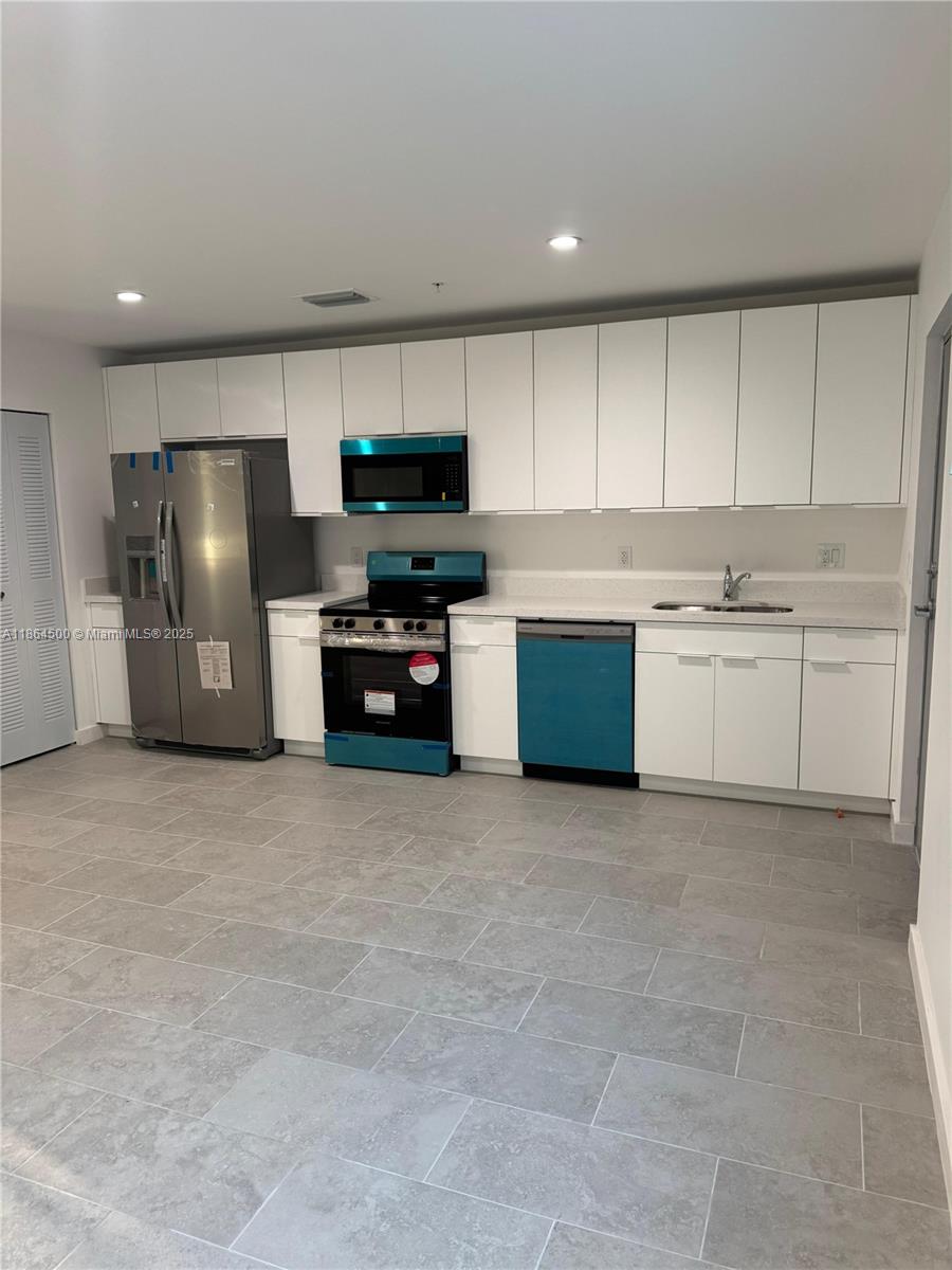 2782 Northwest 46th Street, Unit 5 Miami, FL 33142 - Photo 14 of 18 a kitchen with kitchen island a refrigerator stove and sink