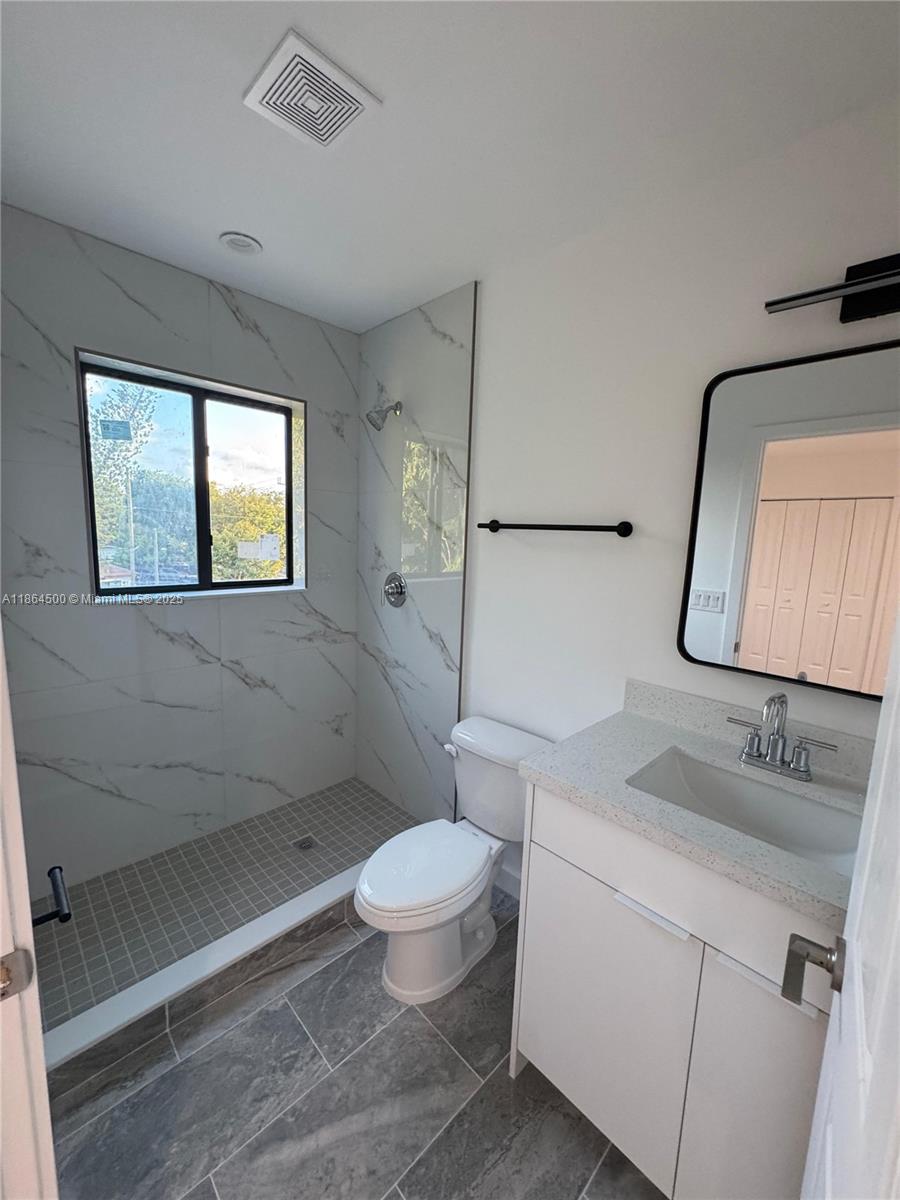 2782 Northwest 46th Street, Unit 5 Miami, FL 33142 - Photo 16 of 18 a bathroom with a granite countertop sink mirror vanity and toilet
