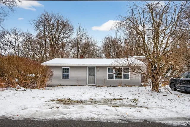 a front view of a house with a yard covered in snow