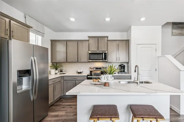 a kitchen with stainless steel appliances a sink a stove a refrigerator cabinets and a counter top space