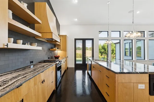 a kitchen with stainless steel appliances granite countertop a sink a stove and a refrigerator
