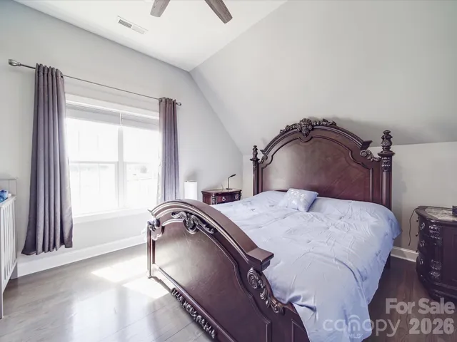 a bedroom with a large bed couch and windows