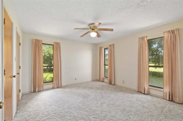 an empty room with windows and fan chandelier