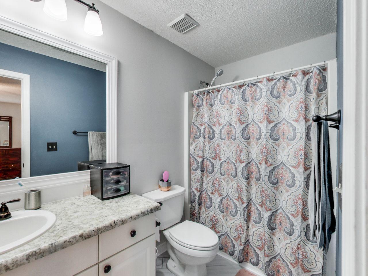 487 Keystone Road, Unit 487 Mary Esther, FL 32569 - Photo 19 of 28 a bathroom with a granite countertop sink a toilet and shower curtain